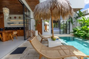 Uma área moderna com piscina ao ar livre, espreguiçadeiras, bar e um grande guarda-sol.