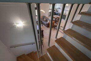 A staircase leading to a living area with a sofa, a dining table, and kitchen cabinets.