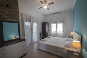 A bedroom with a bed, a TV, a ceiling fan, and a wardrobe.