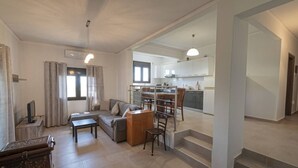 Een moderne woonkamer met een bank, televisie en een eetgedeelte met stoelen en een tafel.