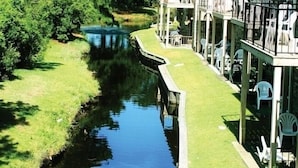 A riverside hotel with a grassy deck, outdoor seating, and a stone building.