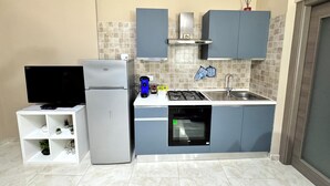 A compact kitchen with a refrigerator, stove, oven, and a small shelf unit. - Modern apartment in the center of Catania, private entrance, up to 6 guests WiFi (Catania)