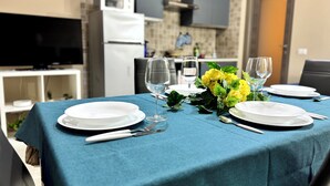 A dining table set with white plates, cutlery, and wine glasses, with a blue tablecloth and yellow flowers. - Modern apartment in the center of Catania, private entrance, up to 6 guests WiFi (Catania)
