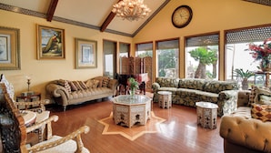 A spacious living room with a high ceiling, wooden flooring, and a variety of seating options including a sofa, armchairs, and a loveseat. - Luxe Waterfront Living: Portland Home w/ Pier! (Portland)