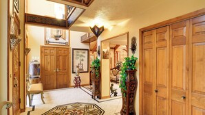 A hallway with wooden doors, a patterned floor, a chair, and a decorative mirror. - Luxe Waterfront Living: Portland Home w/ Pier! (Portland)