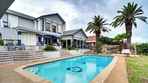 A two-story house with a swimming pool, steps leading to the pool, and palm trees. - Luxe Waterfront Living: Portland Home w/ Pier! (Portland)