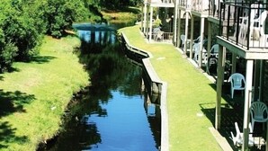 A riverside hotel with a grassy deck, outdoor seating, and a stone building.