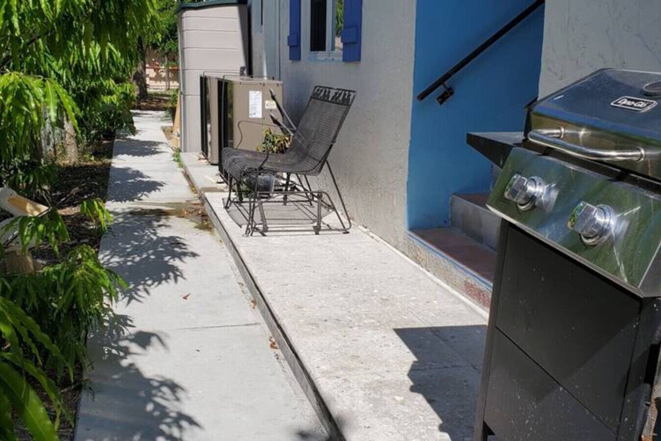 Eine Terrasse mit Grill, Stuhl und kleinem Tisch.