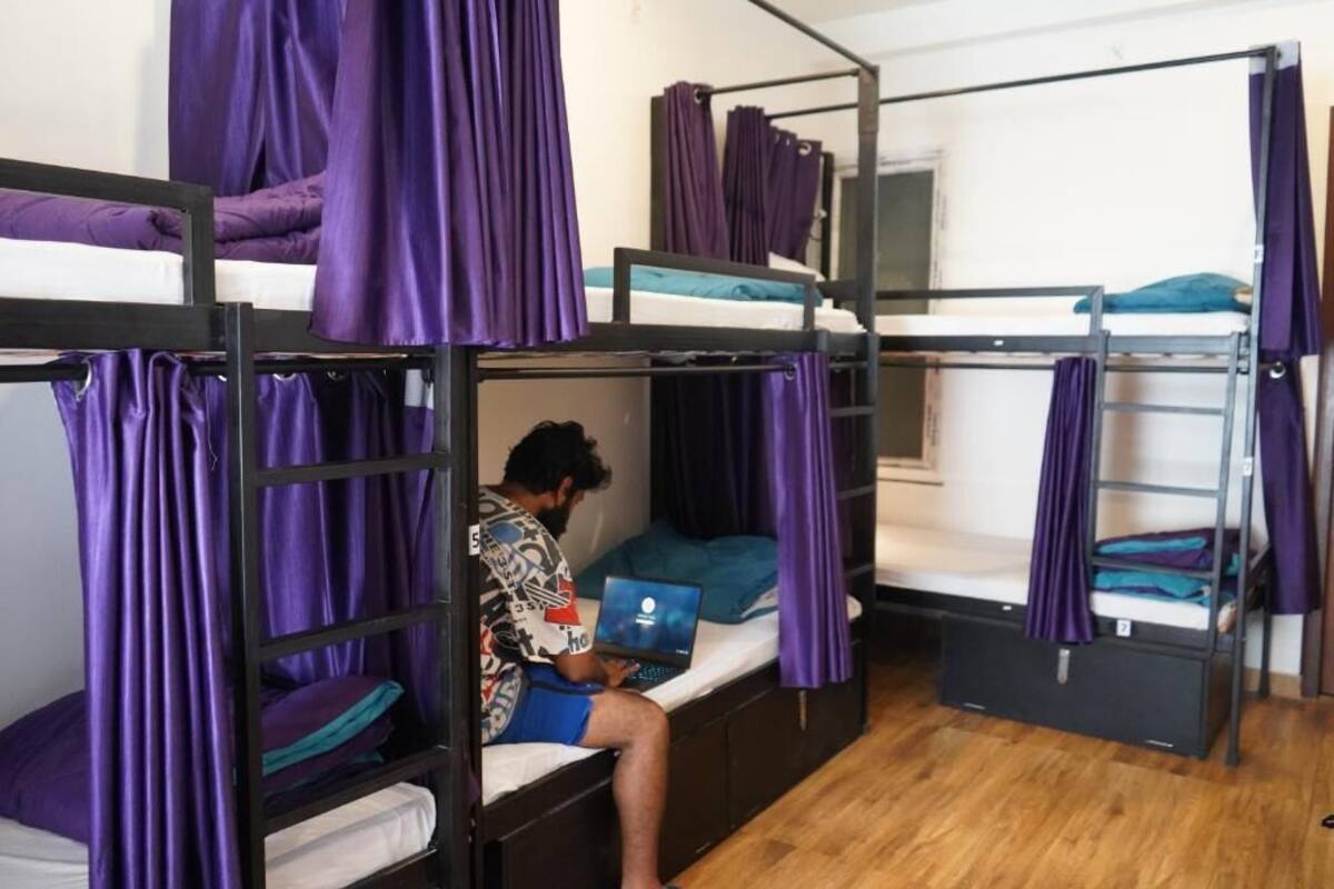 Un dormitorio con literas, cortinas moradas y un ordenador portátil sobre una de las camas.