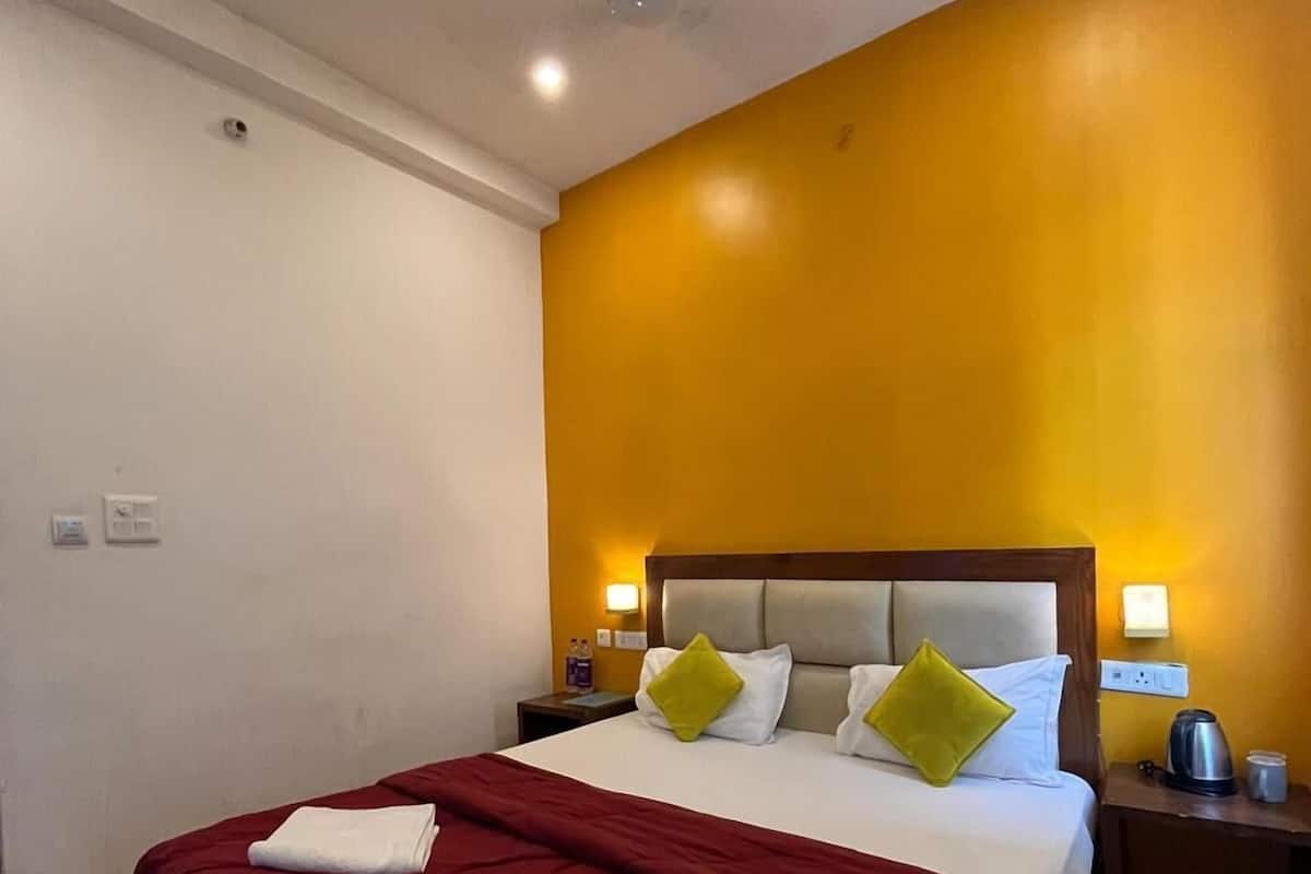 Una habitación de hotel con cama, mesita de noche, ventilador de techo y lámpara en la pared.