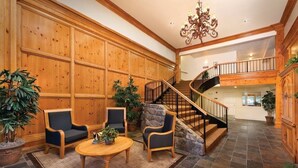 Un vestíbulo espacioso con un revestimiento de madera, una escalera de piedra y un candelabro.