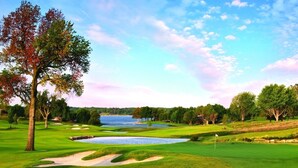 Un campo de golf con búnkeres de arena, un estanque y árboles.