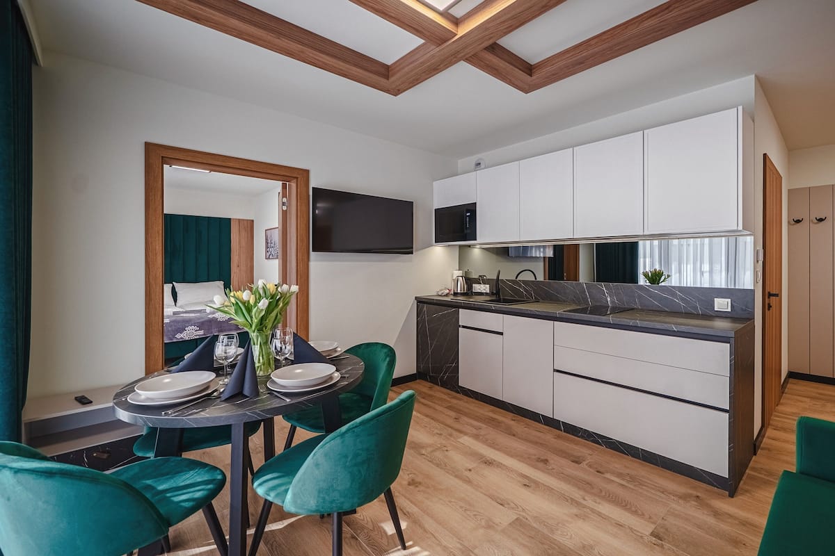 A modern kitchen with white cabinets, a built-in microwave, and a dining area with a table set for two.