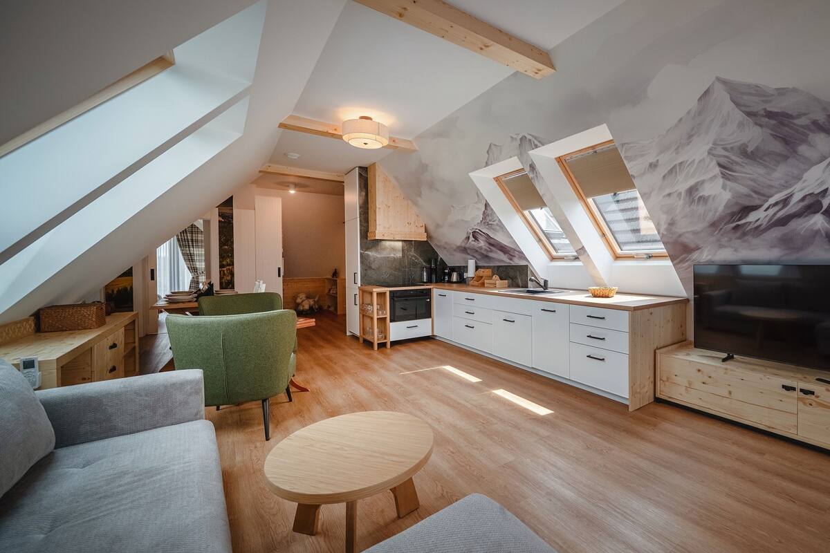 A loft-style living space with a kitchen, dining area, and a large TV.