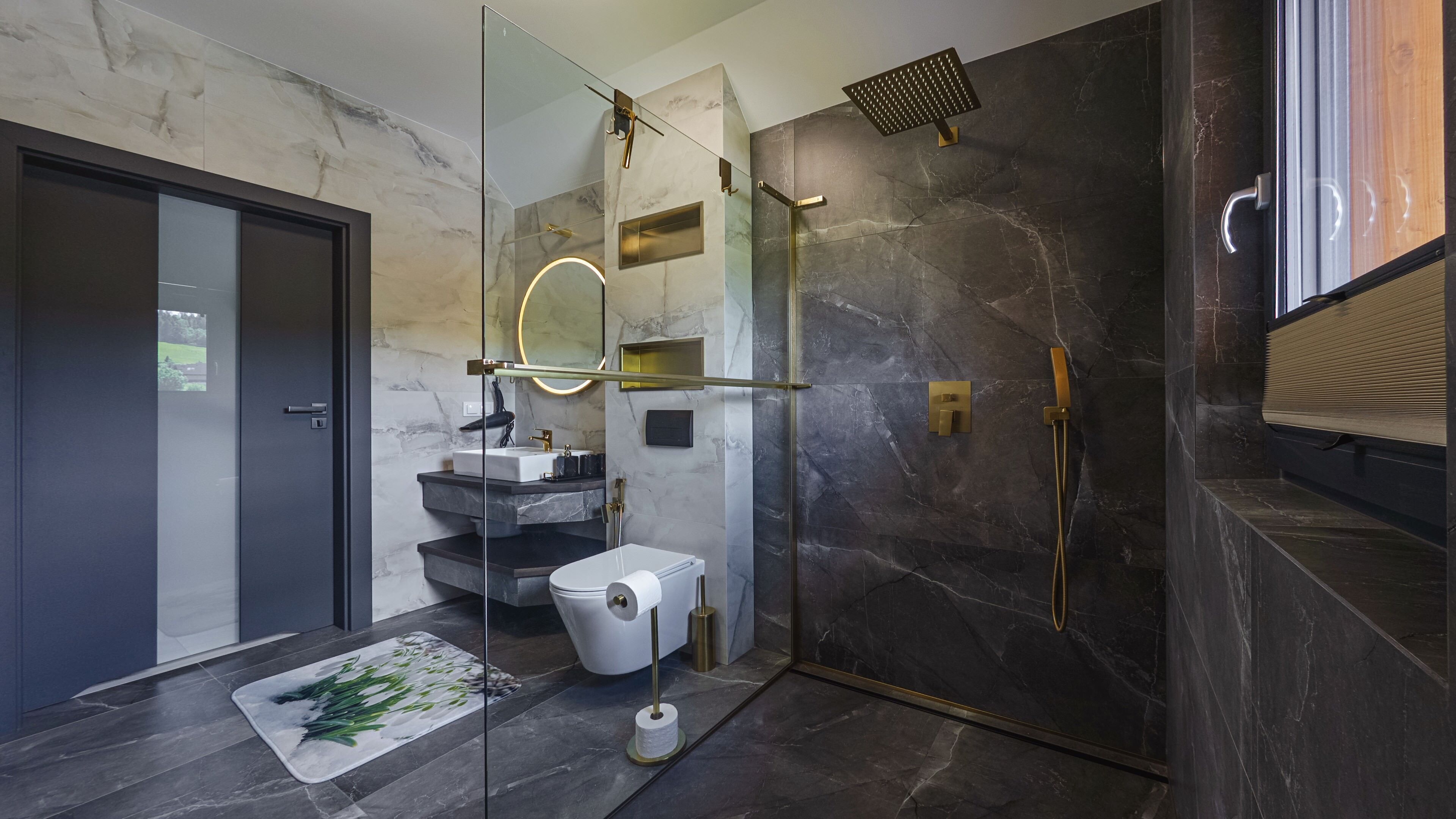 Un baño moderno con ducha de vidrio, inodoro blanco y pared de mármol.