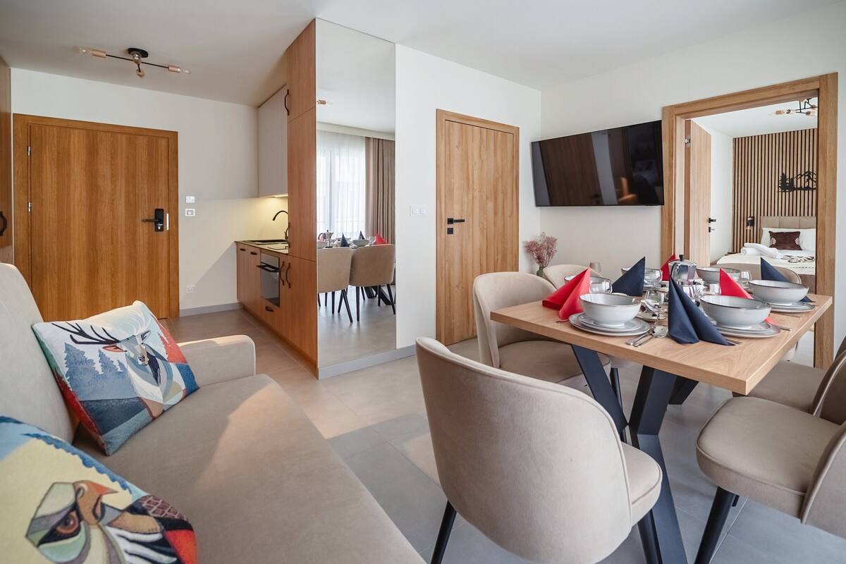 A modern apartment with a dining area, a kitchen, and a living space.