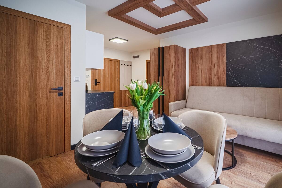 A dining area with a round table, chairs, and a sofa.