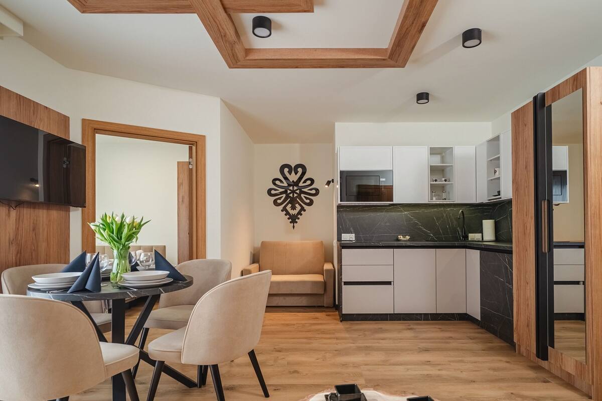 A modern kitchen with wooden cabinets, a marble countertop, and a built-in oven.