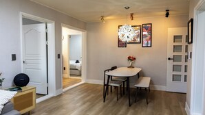 Spiseområde med et bord, stole, en hængende lampe og billeder på væggen.