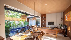 Un área de comedor moderna con una mesa de madera, sillas y vistas a una piscina.