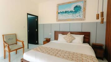 Un cuarto de hotel con una cama, una silla, una mesita de noche, un cabecero de madera y un cuadro en la pared.