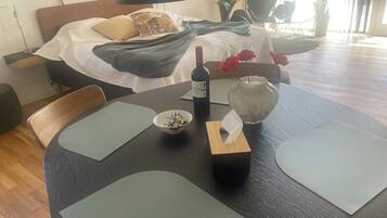 Een keurig ingerichte eethoek met een gedekte tafel voor twee personen, een fles wijn, een schaal met eten en een vaas met rode rozen.