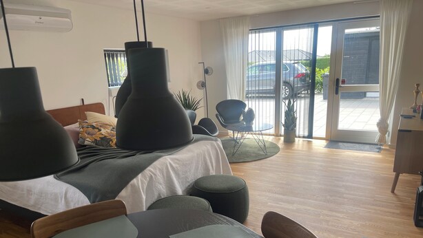 Un dormitorio moderno con cama, mesitas de noche, un escritorio y una zona de comedor con sillas.
