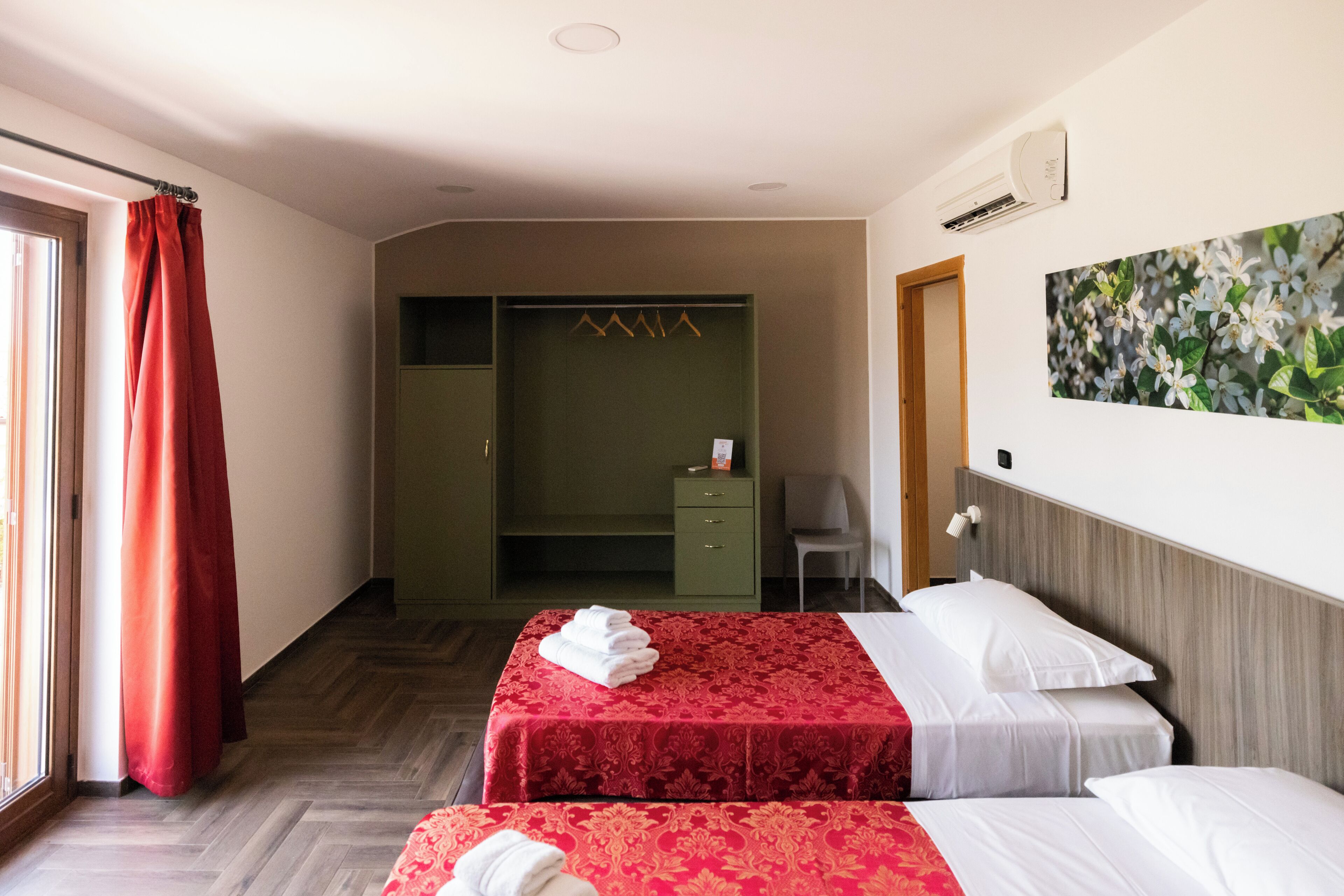 A hotel room with two beds, a wardrobe, a desk, and a chair.