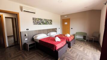 Una habitación de hotel con dos camas, piso de madera, un cuadro en la pared y una puerta.
