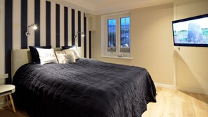 A bedroom with a large bed, a window with a view, a TV, and a striped wall. - Modern 93sqm on 2 levels for up to 4 people with its own sauna - (Sylt)