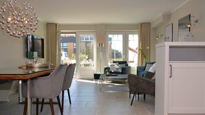 A spacious living area with a dining table, chairs, a sofa, and a cabinet. - Modern 93sqm on 2 levels for up to 4 people with its own sauna - (Sylt)