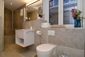 Ein modernes Badezimmer mit Dusche, Waschbecken, Toilette und einem Schminktisch mit Spiegel.