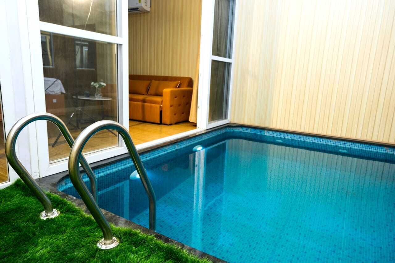 Une piscine avec une paroi en verre, un canapé à l’arrière-plan et une porte donnant sur une pièce.