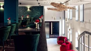 Un interior moderno con sillas tapizadas de verde, una butaca roja y una escultura única en el techo.