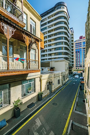 A street view with a building featuring balconies and a modern high-rise in the background. - Nizami Avenue Hotel (Baku)