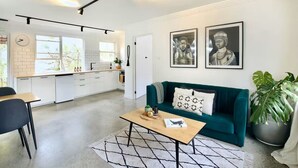 Een moderne woonruimte met een blauwgroene bank, een bijzettafeltje en kunst aan de muur.