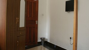 Ett rum med en garderob i trä, en dörr, en papperskorg och en väggmonterad tv.