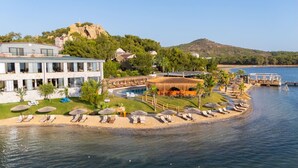 A coastal hotel with a pool, beach chairs, umbrellas, and a view of the sea and hills. - Khaja Beach Hotel (Ayvalik)