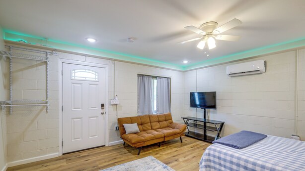 Una habitación con cama, sofá, televisión y ventilador de techo.