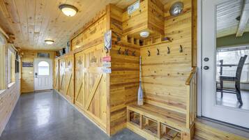 Interior de madera con un banco, una puerta y una pala fijada a la pared.