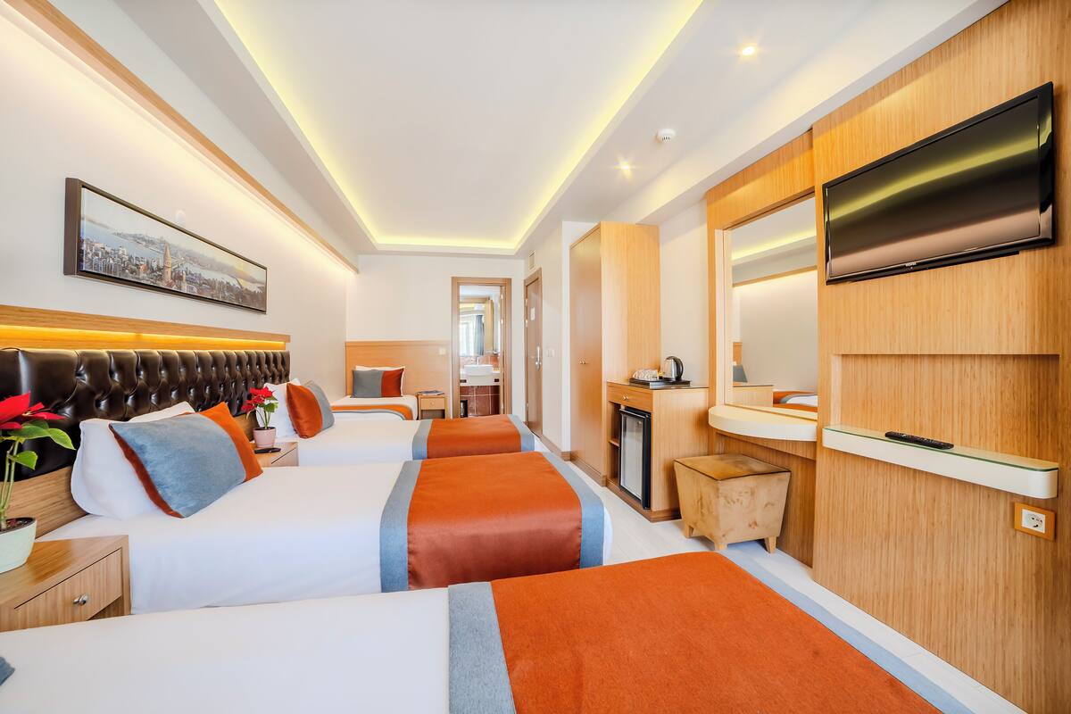 Habitación de hotel con dos camas, televisión, baño y vistas a la ciudad.