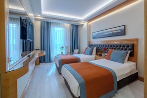 A hotel room with two beds, a TV, a desk, and a window with curtains. - REŞİTPAŞA HOTEL (İstanbul)