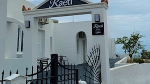 A white building with a black sign reading 'Raeti Fira Residence' above the entrance. - Raeti Fira Residence (Santorini)