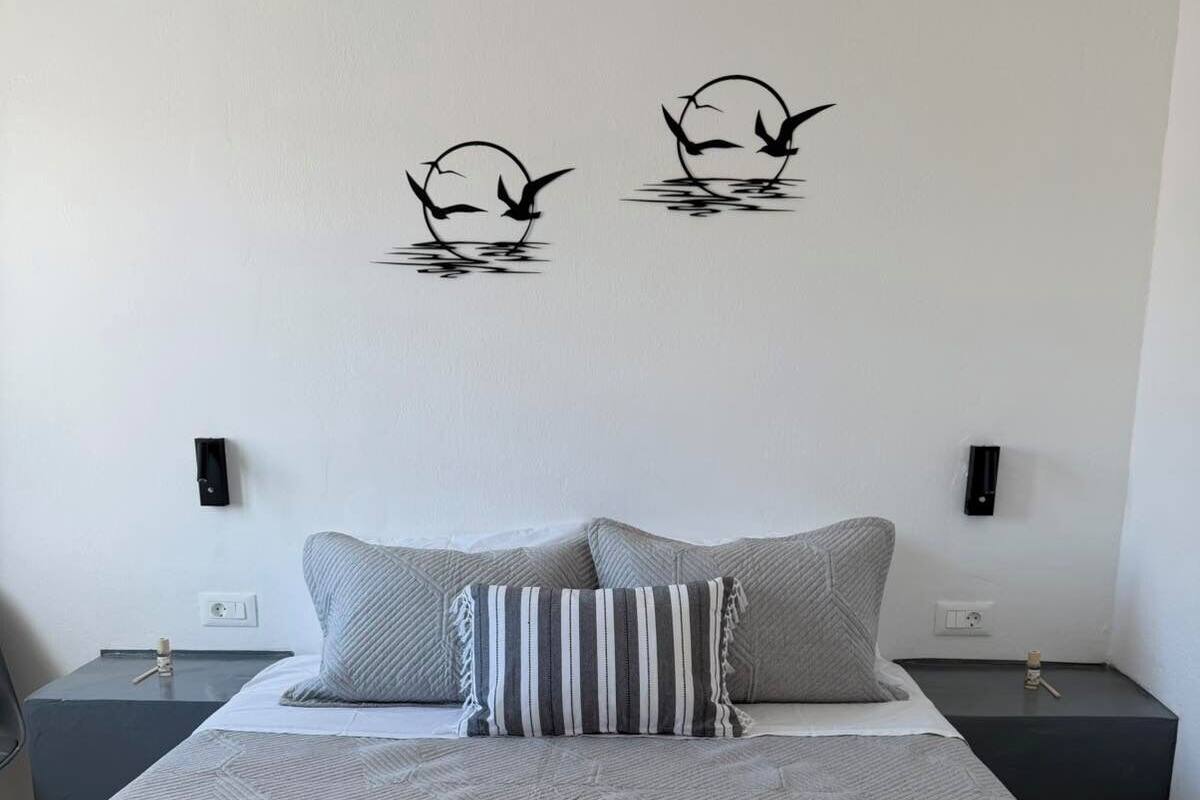 Ein ordentlich bezogenes Bett mit einem geometrisch gemusterten Überwurf, zwei Kissen und einem gefalteten Handtuch auf der Seite.