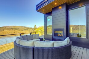 Un área de estar moderna al aire libre con una chimenea incorporada, con vistas a un paisaje pintoresco.