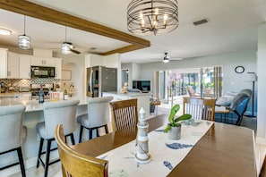A modern kitchen with a dining area, wooden ceiling beams, and a large window. - Private Yard + Heated Pool: Port Charlotte Oasis (Port Charlotte)