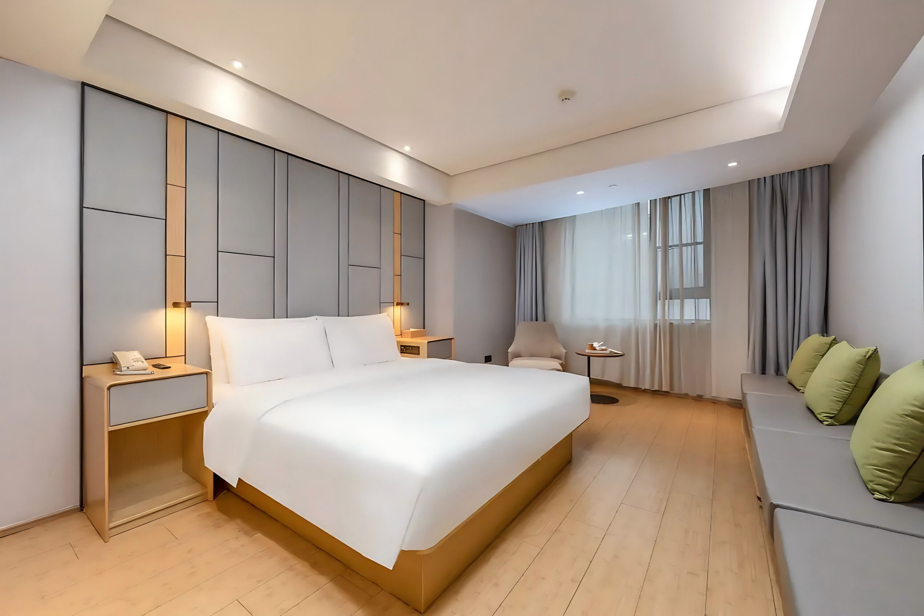 A modern hotel room with a large bed, bedside tables, a desk, and a seating area.