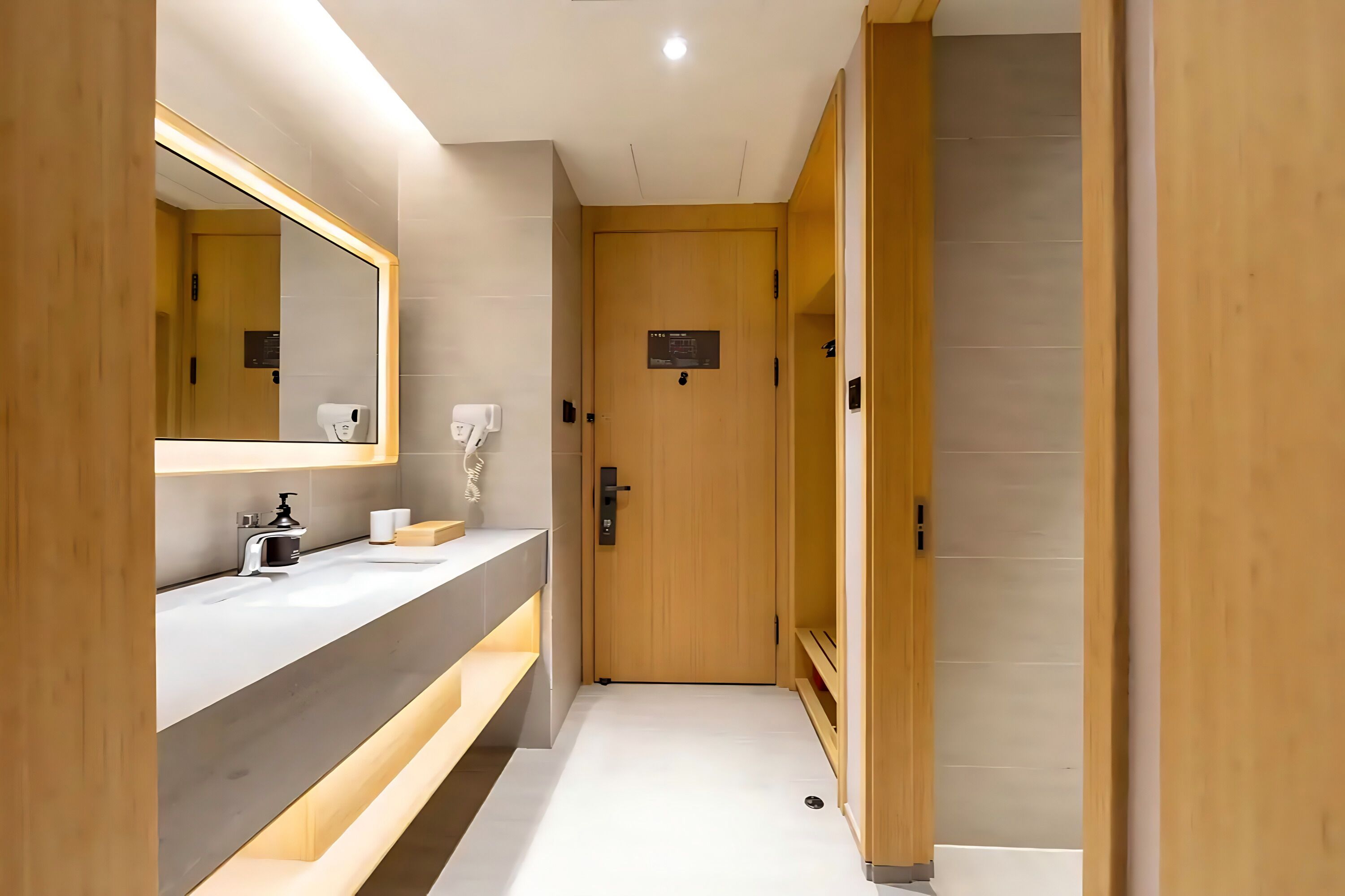 Een moderne badkamer met een grote spiegel, een wastafel, een zeepdispenser en een houten deur.