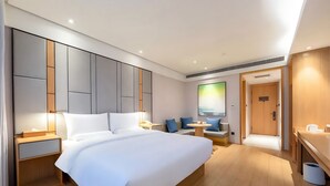 A modern hotel room with a large bed, bedside tables, a seating area with a small table, and a door leading to another room. - Ji Hotel Wuhan Hankou Xinhua Road (Wuhan)