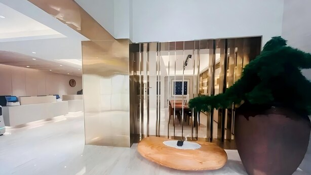 A modern hotel lobby with a reception desk, a large potted plant, and a decorative wall feature. - Ji Hotel Wuhan Hankou Xinhua Road (Wuhan)